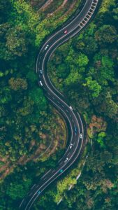 A road winding through a forest with cars driving along.