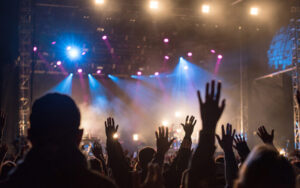 Hands raised in a contemporary worship service with lights and fog in the background.